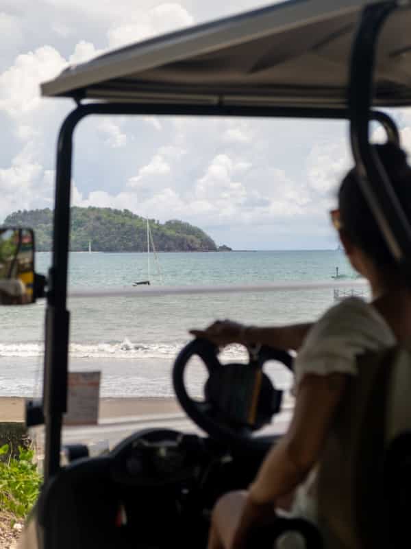 A girl sitting in a golf cart looking at the Beach in Tamarindo